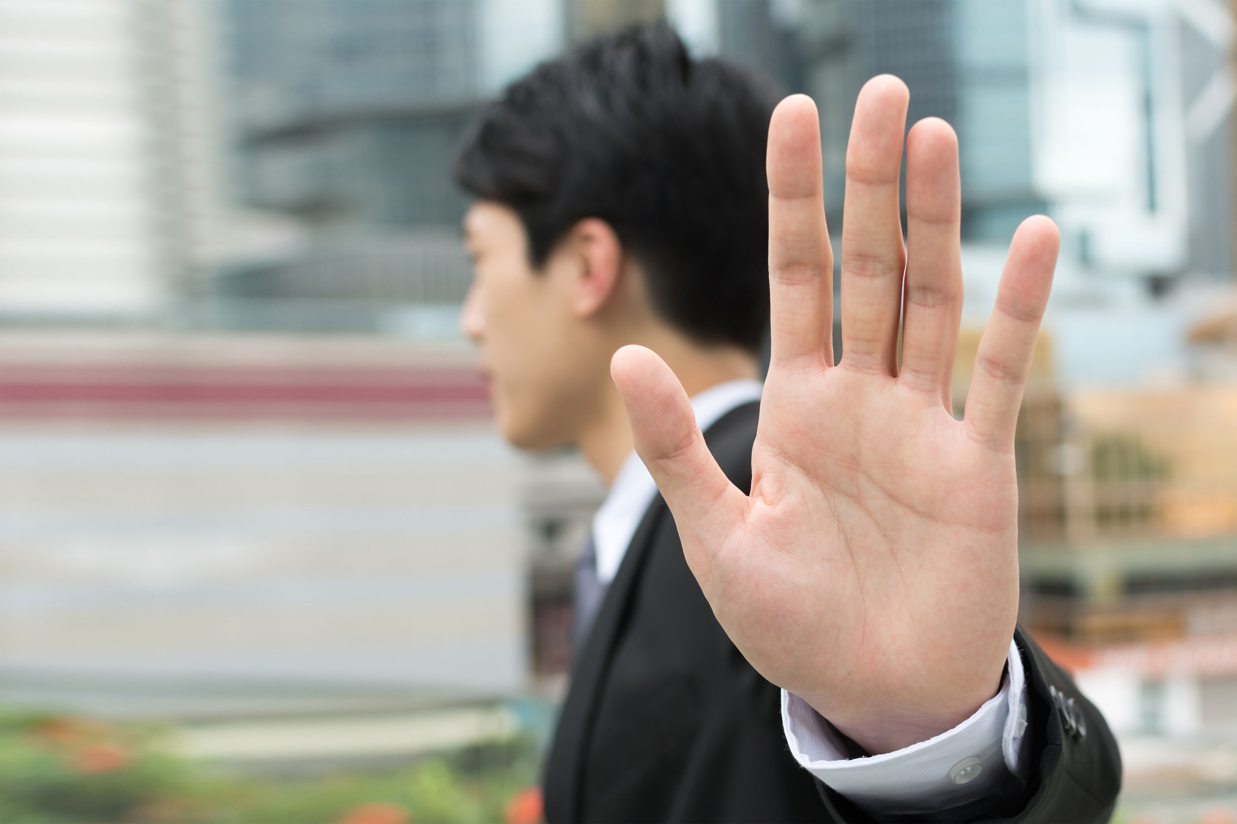 stop gesture, side view of asian businessman standing in the city.